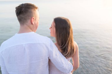 Plaj çifti arkadan okyanus manzarasına bakıyor. Tropik destinasyonda yaz seyahattatillerinde dinlendirici