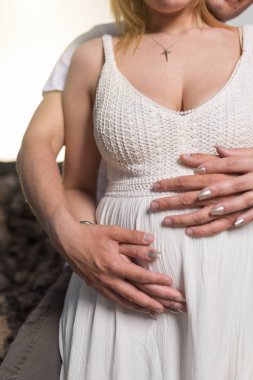 Hamile karısının karnını tutan adam. Hamile kadın ve sevgi dolu koca sahilde karın sarılma. 