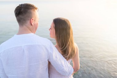 Plaj çifti arkadan okyanus manzarasına bakıyor. Tropik destinasyonda yaz seyahattatillerinde dinlendirici