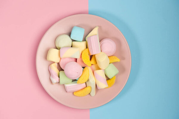 Розовая тарелка с зефиром, изолированная на голубом и розовом фоне. Вид сверху
.