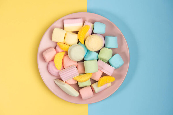 Розовая пластинка с зефиром, изолирована на синем и желтом, задний план. Вид сверху
.