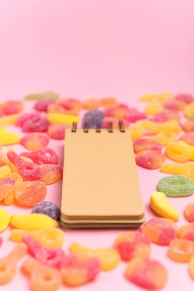 Coral paper background with sweets and blank notepad. Place for your text. Cozy sweet background