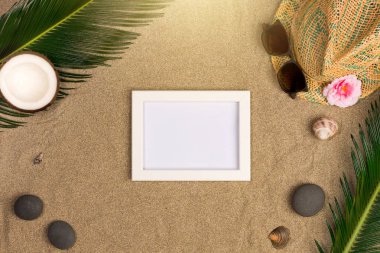 Fotoğraf çerçevesi, yeşil yaprakları, şapka ve kum arka plan üzerinde güneş gözlüğü ile şık yaz kompozisyon. Kopya alanı ile sanat mockup