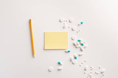 Not defteri, beyaz arka plan üzerinde kalem ve haplar. Tedavi konsepti. Düz yatma.