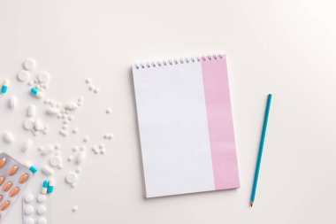 Beyaz arka planda ilaç, kalem ve defter. Tıbbi kavram. Düz yatma.