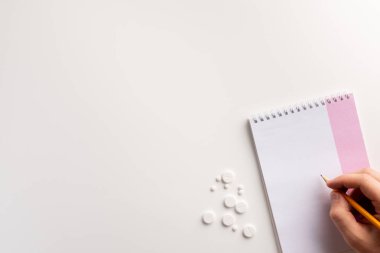 Mle el, not defteri, kalem, beyaz arka plan üzerinde uyuşturucu. Düz yatıyordu