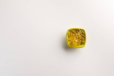 Beyaz arka plan üzerinde izole balık yağı kapsülleri ile Kase. Düz yatıyordu.