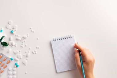 Femle el, not defteri, kalem, beyaz arka plan üzerinde uyuşturucu