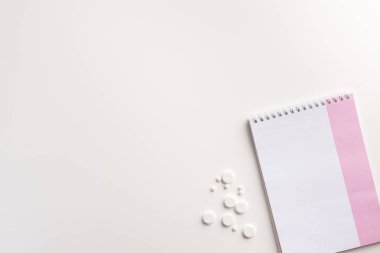 Beyaz arka planda defter ve haplar. Düz yatıyordu.