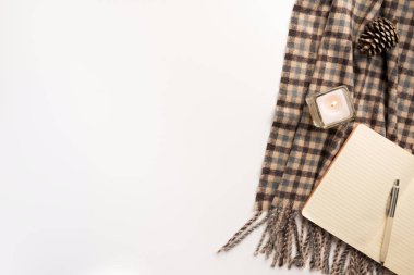 Açık defter, atkı, mum, beyaz arka plan üzerinde. Düz yatıyordu.