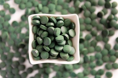 Beyaz arka planda Spirulina tabletler. Düz yatıyordu.
