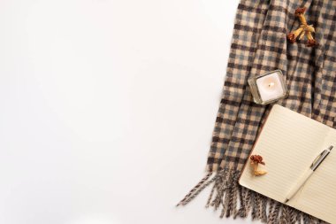 Açık defter, atkı, mum, beyaz arka plan üzerinde. Düz yatıyordu.