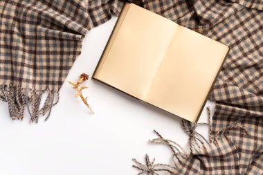 Açık kitap ve eşarp, beyaz bir arka plan üzerinde. Düz yatıyordu.