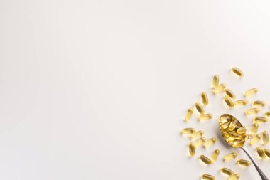 Balık yağı kapsülleri ile Kaşık, beyaz arka plan üzerinde izole. Düz yatıyordu.