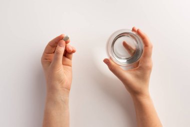Sağlık ve tıbbi kavram. Bir elinde hap tutan kişi, diğer elinde bir bardak su. Düz yatıyordu.