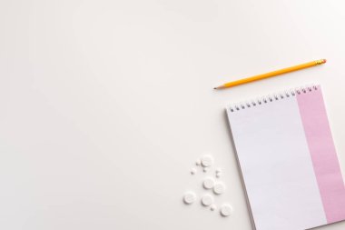 Beyaz arka planda defter, kalem ve haplar. Tıbbi konsept. Düz yatıyordu.