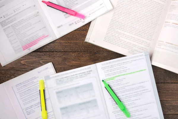 Remote education concept. Open books and coloured pens on wooden desk, flat lay