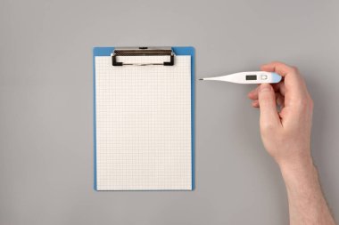 Covid-19 'u durdurun. Erkekler termometreyi tutuyor. Gri arka planda düz yatıyordu. Coronavirus hastalığı tedavisi. Sıcaklık ölçümü. Hijyen, sağlık ve koruma teması