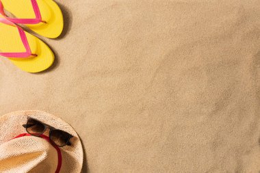 Yaz tatili kompozisyonu. Terlikler ve hasır şapkalar kumun üzerinde 