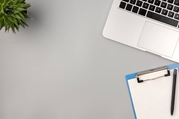 Квартира лежала, стол с видом сверху. Рабочее место врача с ноутбуком, блокнотом и домашним растением на столе. Серый фон
.