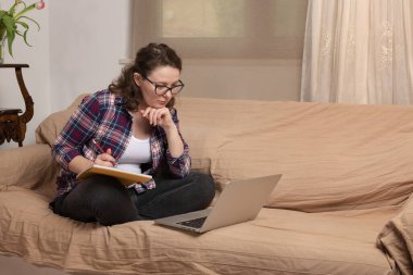 Coronavirus. Karantinaya alın. Evde eğitim, eğitim ve serbest çalışma. Yetişkin bir kadın evde bilgisayarla ve kitaplarla uzaktan çalışıyor. Dünyada koronavirüs salgını.