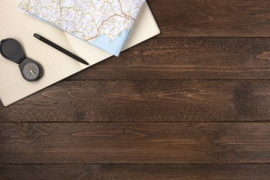 Harita ve açık defter izole, ahşap arka planda. Düz konum, üst görünüm, kopyalama alanı.