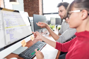 Erkek ve kadın programcılar bilgisayarda yazılım kodu ile çalışma