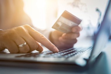 Kredi kartı tutan ve dizüstü bilgisayar kullanarak eller. Online ödeme ve alışveriş kavramı.