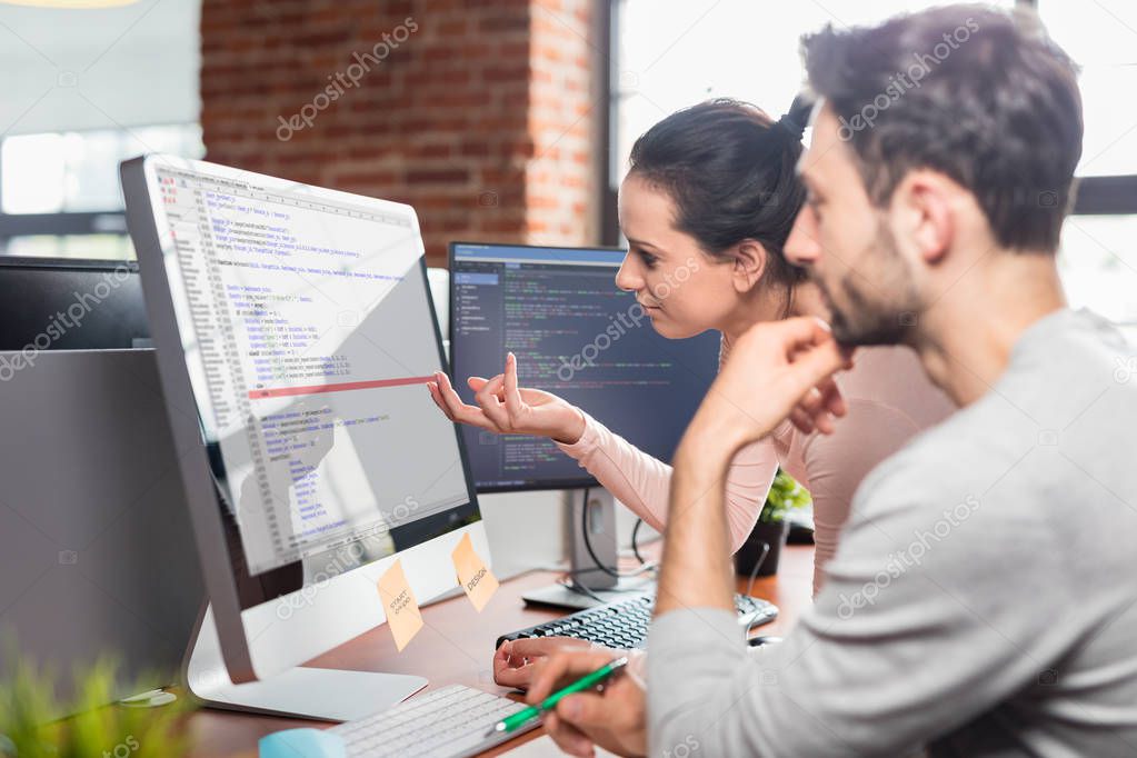 man and woman programmers working with software code on computer