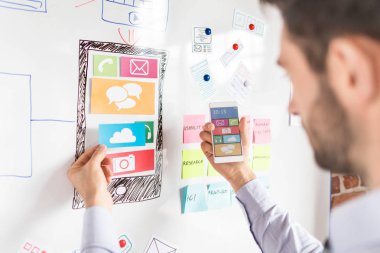 Web sitesi ux app geliştirme çizim ve akıllı telefon elinde tutan tasarımcı adam