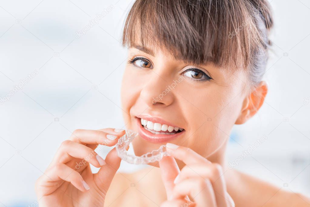 Woman wearing orthodontic silicone trainer. Invisible braces aligner. 
