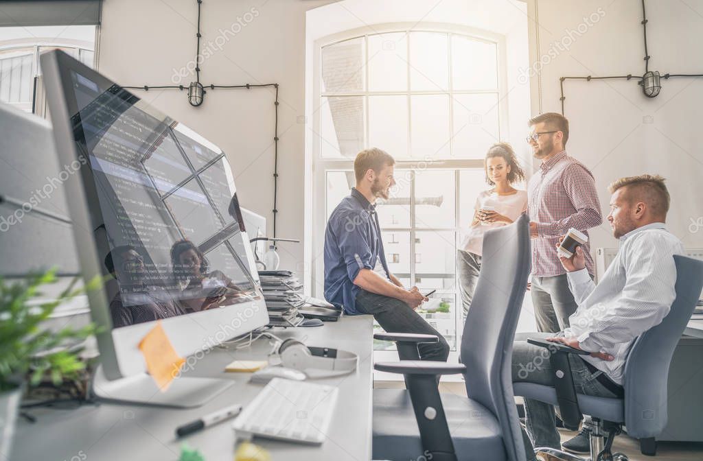 team interacting in office with computer screen on foreground