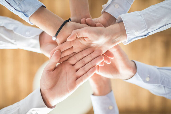 top view of young business people putting hands together