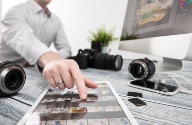 Fotoğrafçı transfer dosyaları dijital tablet bilgisayara kamera ve lens ile masa üzerinde