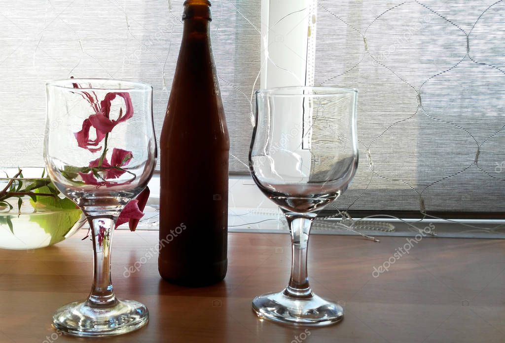 two glasses, a bottle of a flower in a vase