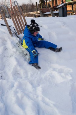 Kış sırasında zledge ile oynayan küçük bir çocuk