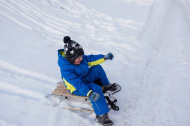 Kış sırasında zledge ile oynayan küçük bir çocuk