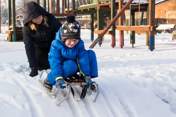 Kış sırasında zledge ile oynayan küçük bir çocuk