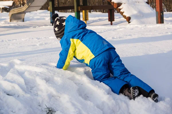 雪に覆われた丘に登る小さな男の子 — ストック写真