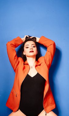  Siyah vücut ve turuncu ceket giyen, mavi arka planda, zıt görüşlü genç bir kız.          