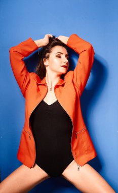  Siyah vücut ve turuncu ceket giyen, mavi arka planda, zıt görüşlü genç bir kız.          