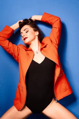  Siyah vücut ve turuncu ceket giyen, mavi arka planda, zıt görüşlü genç bir kız.          