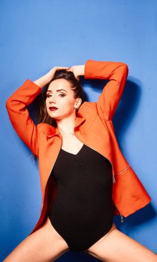  Siyah vücut ve turuncu ceket giyen, mavi arka planda, zıt görüşlü genç bir kız.          