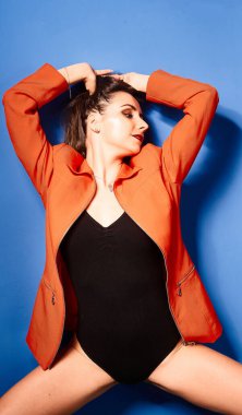  Siyah vücut ve turuncu ceket giyen, mavi arka planda, zıt görüşlü genç bir kız.          