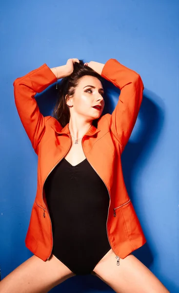 素敵な若い白い女の子は 黒のボディとオレンジのジャケット 青の背景を着て 非常に対照的な画像 — ストック写真