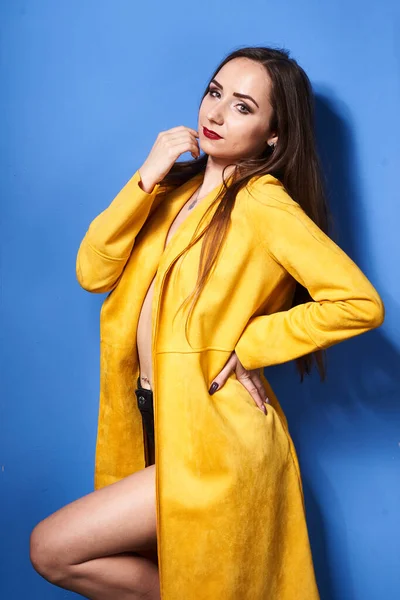 Een Mooi Meisje Poseert Een Gele Jas Tegen Een Blauwe — Stockfoto