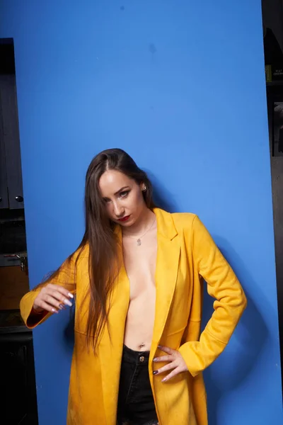 Una Bella Ragazza Posa Cappotto Giallo Contro Muro Blu — Foto Stock