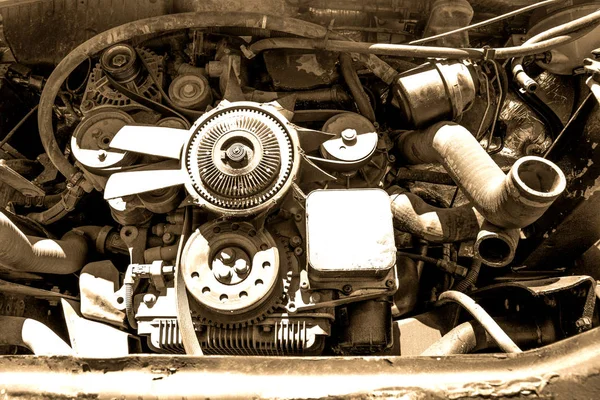 Old broken and dirty car engine close up, view under the hood in sepia tones