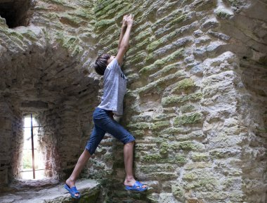 Eski kule eski taş duvara tırmanmaya çalışan genç çocuk