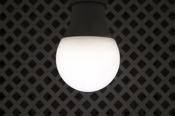 Современная Круглая Энергосберегающая Лампочка Фоне Ромбованной Решетки — стоковое фото
